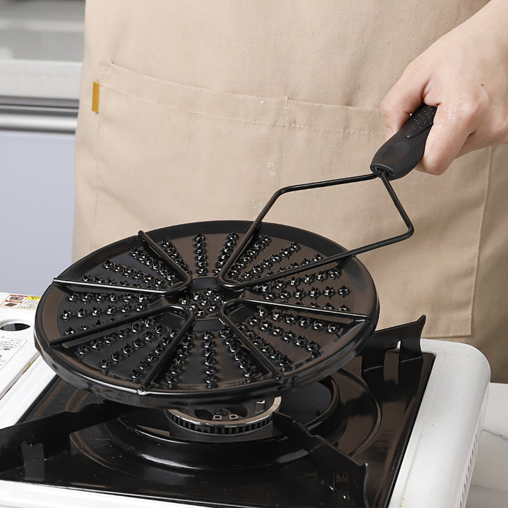 Black cast iron heat distribution pad for even cooking on a gas stove