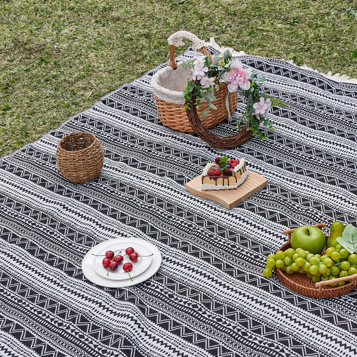 Gewebte Picknickdecke mit schwarz-weißem Streifenmuster ausgebreitet im Freien
