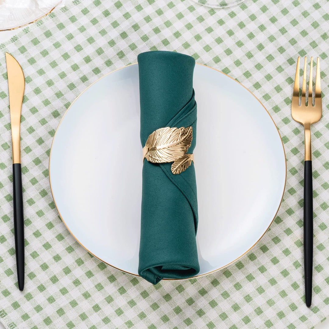 Goldene Serviettenringe mit weißen Stoffservietten auf elegantem Gedeck