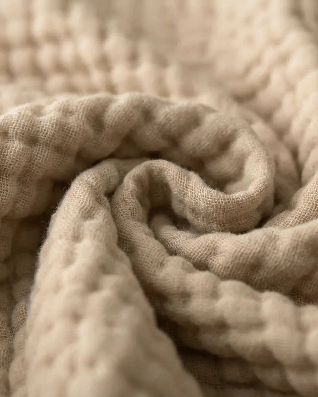 Atmungsaktive Wohndecke aus Musselin gefaltet auf einem Bett