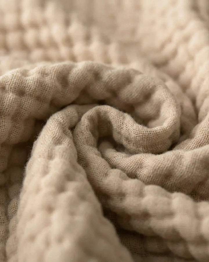 Atmungsaktive Wohndecke aus Musselin gefaltet auf einem Bett