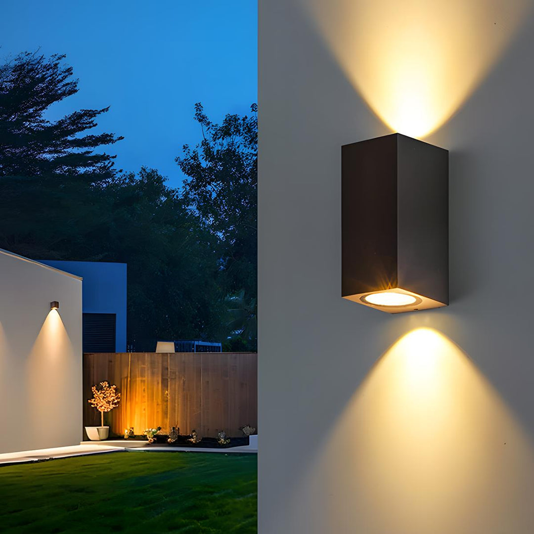 Quadratische Außenwandleuchte mit warmem Licht an einer Terrassenwand